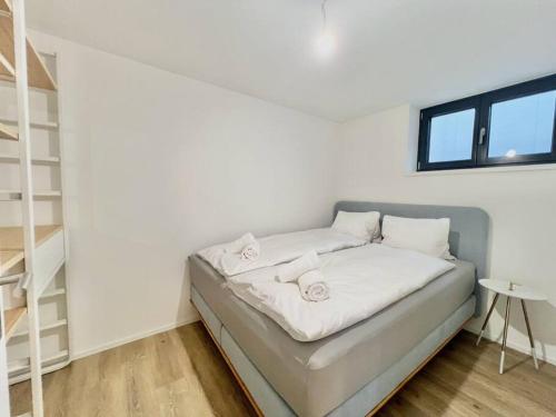 Una cama con sábanas blancas y toallas en una habitación en The R Apartment Roggen, new, Parking, washing machine, en Kestenholz