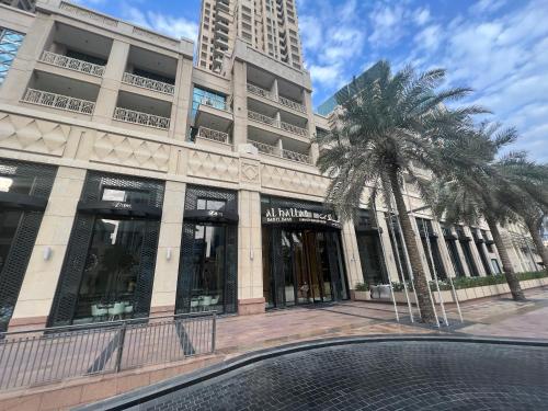 a building with a palm tree in front of it at Prestige Living 2BR with Full Burj Khalifa and Fountain View by Auberge in Dubai