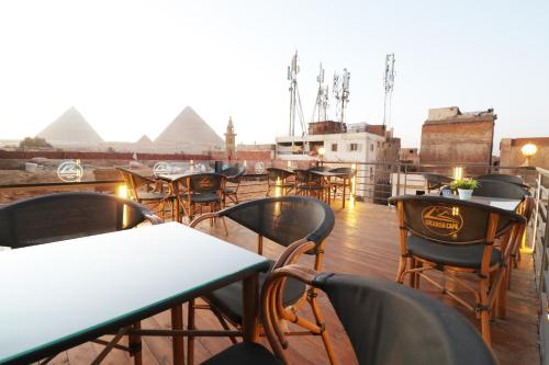 Locanda Pyramids Hotel في القاهرة: صف من الطاولات والكراسي في السطح مع الاهرامات