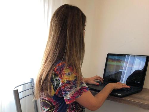 una mujer con el pelo largo escribiendo en un ordenador portátil en HOTEL ROMA DE TANDIL en Tandil
