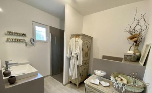 La salle de bains est pourvue d'un lavabo et d'un peignoir blanc sur une armoire. dans l'établissement La villa les parfums d’Ete, à Ornaisons