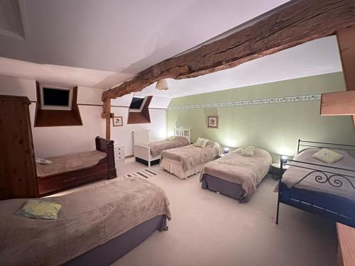 a hotel room with three beds and a tv at Le Mesnil Gonfroy, A Haven Of Tranquility in Hambye