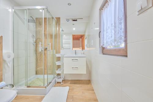 a white bathroom with a shower and a sink at Agroturystyka Barycz Całoroczny Domek Marcel in Końskie