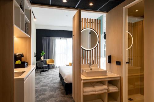 Habitación de hotel con cama, lavabo y espejo en Otium Hotel Roosendaal en Roosendaal