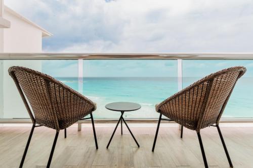 two chairs and a table in front of a window at The Oceanfront by Casa Paraiso in Cancún