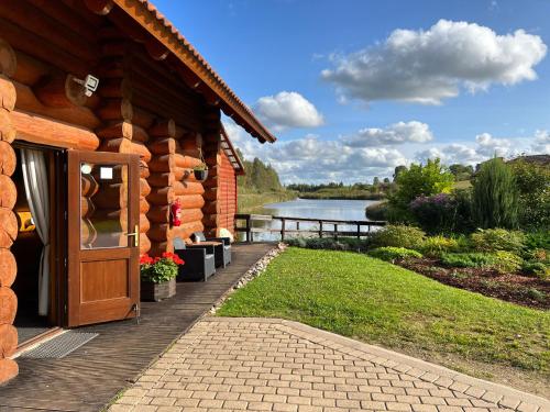 a log cabin with a door and a view of a lake at Kundziņu salas in Vidriži