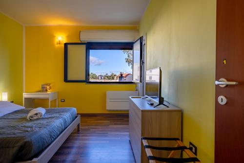 een gele kamer met een bed en een raam bij Holos Apartment in Capoterra