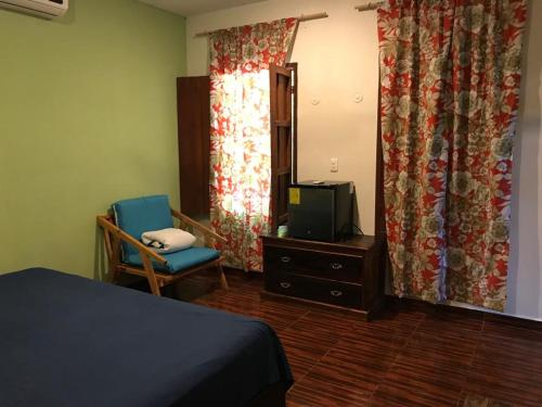 um quarto com uma cama, uma televisão e uma cadeira em El Callejón em Valladolid