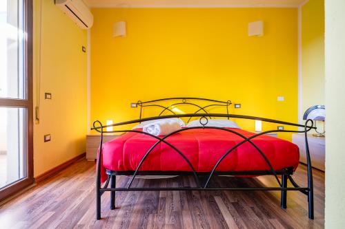 een slaapkamer met een rood bed in een gele muur bij Holos Apartment in Capoterra