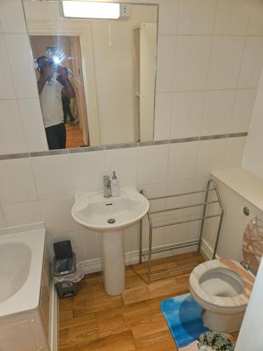 a bathroom with a sink and a toilet and a mirror at HEATHROW MANSION SHUTTLES in Uxbridge