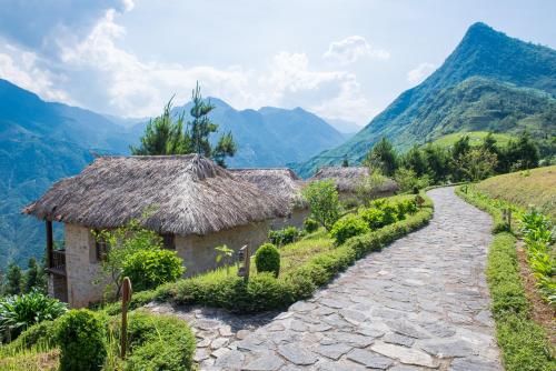 a path through a village with mountains in the background at Topas Ecolodge in Sa Pa