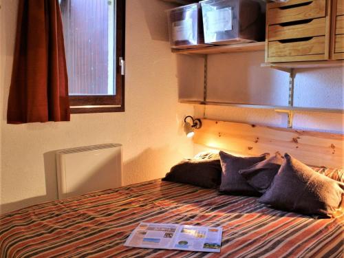 Un dormitorio con una cama con un libro. en Appartement Risoul, 2 pièces, 4 personnes - FR-1-330-520, en Risoul