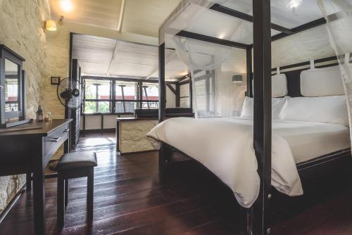 a bedroom with a large bed and a desk at Rabot Hotel From Hotel Chocolat in Soufrière