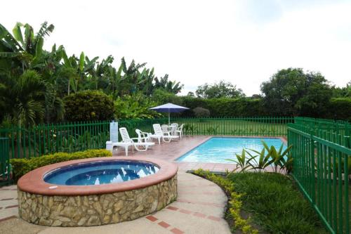 una pequeña piscina con sillas, mesa y sombrilla en Finca Hotel Betulia, en La Tebaida