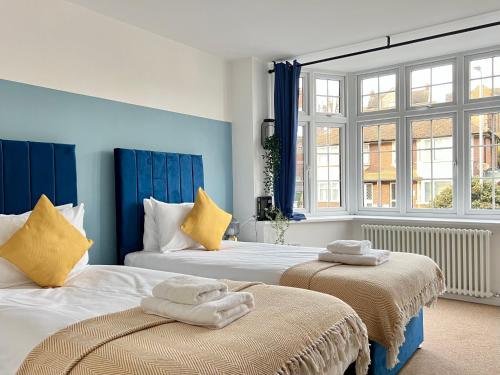 - 2 lits dans une chambre aux murs bleus et aux fenêtres dans l'établissement Perfect Place For Contractors & Family Stays, à Luton