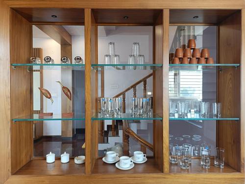 a cabinet filled with glasses and cups on display at CasaBonito 3BHK Villa in Mysore