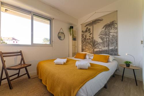Cette chambre comprend un grand lit avec des draps jaunes et une chaise. dans l'établissement La Jetée du Moulleau - Appt 4 personnes vue Bassin, à Arcachon
