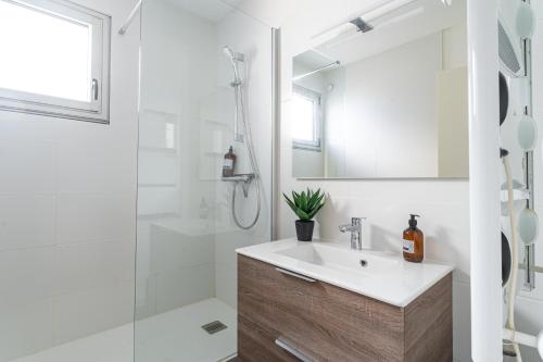 une salle de bain blanche avec un lavabo et une douche dans l'établissement La Jetée du Moulleau - Appt 4 personnes vue Bassin, à Arcachon