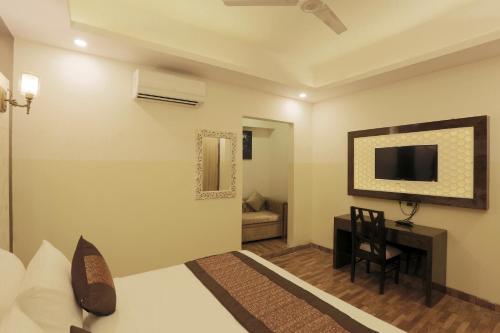 a bedroom with a bed and a desk and a television at Plazzo Prime Plaza in New Delhi