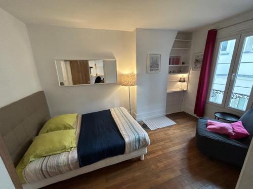 een slaapkamer met een bed, een bank en een spiegel bij Paris Sacré Coeur et Tour Eiffel in Parijs