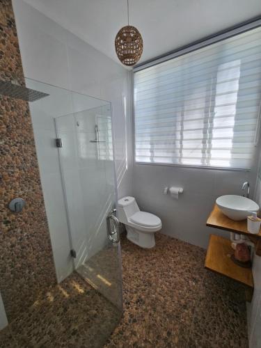 a bathroom with a shower and a toilet and a sink at Sunset Surf Villa in La Libertad