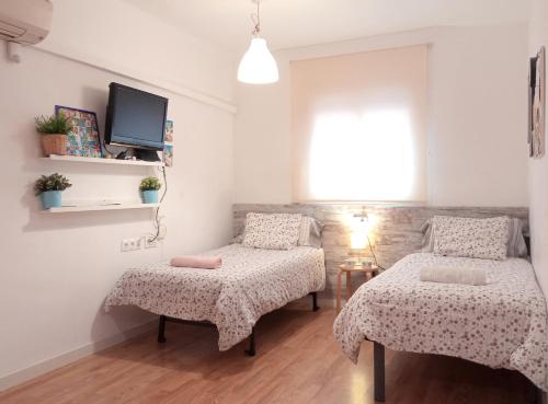 a bedroom with two beds and a tv on the wall at bcn4days Apartments in Hospitalet de Llobregat