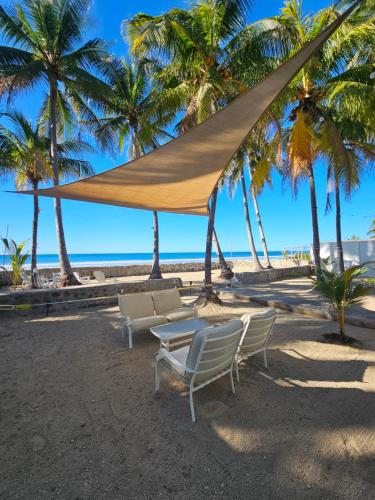 a table and chairs on a beach with palm trees at Sunset Surf Villa in La Libertad