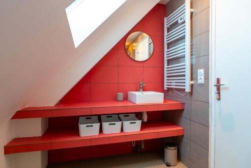 La salle de bains est pourvue d'un lavabo et d'un mur rouge. dans l'établissement Portamaneg - Grande maison familiale Port-Manech, à Névez