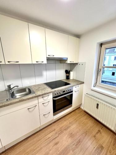 a kitchen with white cabinets and a sink and a window at Stilvolles Wohnen am Hafen in Bregenz