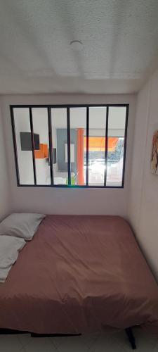 un lit dans une chambre avec une grande fenêtre dans l'établissement Studio 25m2/côté couchant-plages & commerces, à La Grande Motte