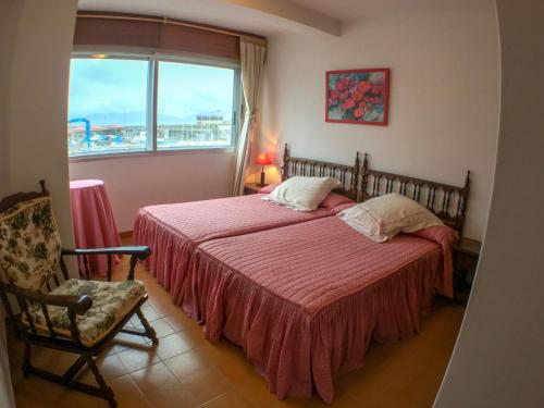 1 dormitorio con cama, ventana y silla en Apartamento con excelente localización y vistas al mar, en Sanxenxo