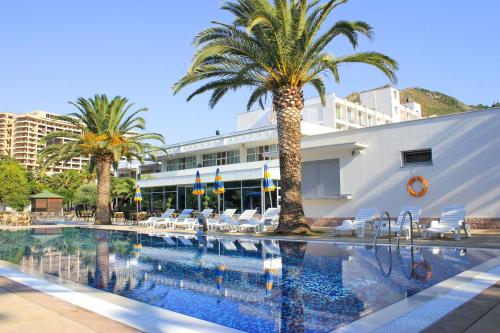 een zwembad met palmbomen en stoelen en een gebouw bij Hotel Montenegro in Budva