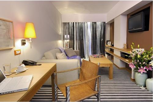 a living room with a couch and a desk with a laptop at Galaxy City Center Hotel in Patra