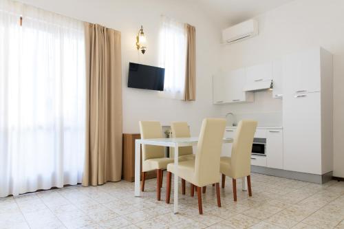 una sala da pranzo con tavolo e sedie bianchi di Residence Oasi a Limone sul Garda