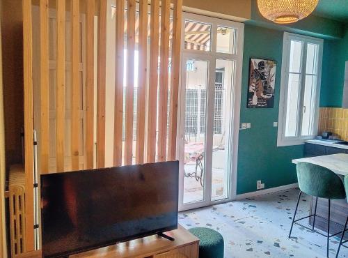 un salon avec une télévision à écran plat devant une porte dans l'établissement Résidence Le Lérins, à Juan-les-Pins