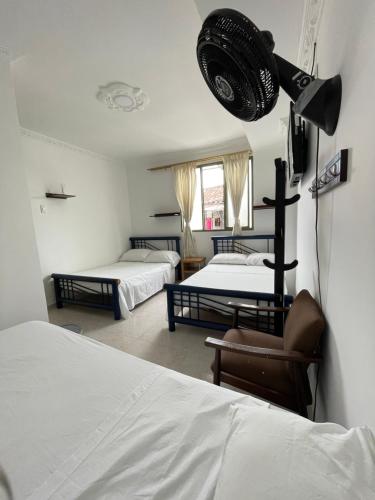 een slaapkamer met 2 bedden en een stoel en een spotlight bij Hotel California Tropical in La Tebaida