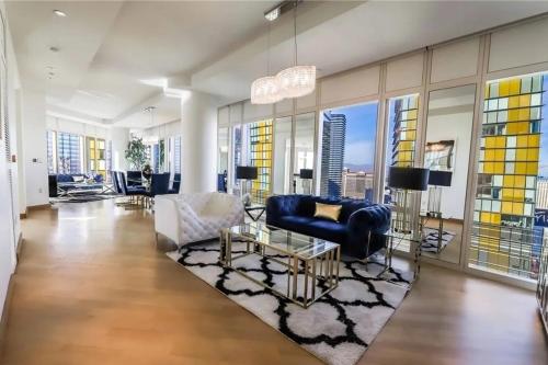 a living room with a blue couch and chairs at Elegant Corner 2 Bedroom Condo with Floor to Ceiling Windows in Las Vegas