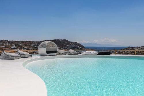 a swimming pool with chairs and a view of the ocean at Villa Sera Mykonos in Glastros