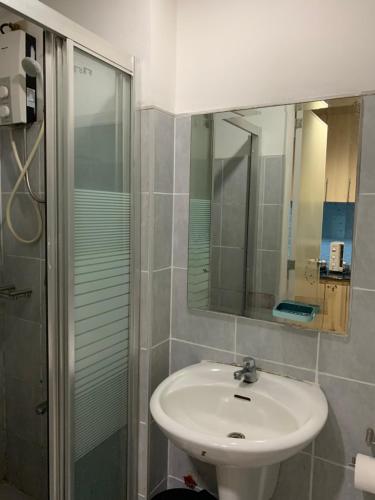a bathroom with a sink and a shower with a mirror at Moa staycation in Manila