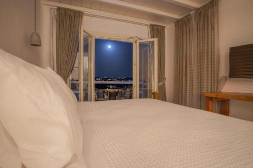 a bedroom with a large white bed and a window at Villa Sera Mykonos in Glastros