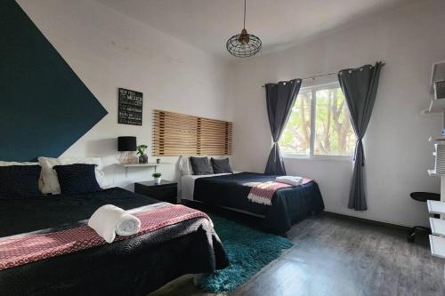 Un dormitorio con dos camas y una ventana. en Casa Balam Condesa, en Ciudad de México