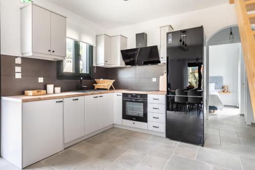 a kitchen with white cabinets and black appliances at Marani Home & Villas in Skopelos Town