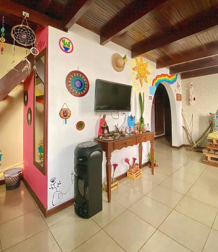 Habitación con pared, TV y mesa. en CasAMARelo Hostel en Salvador