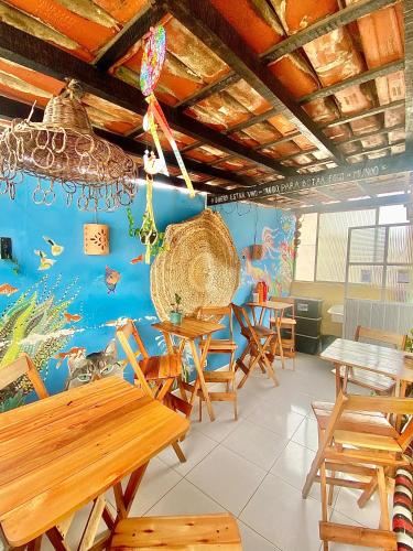 a restaurant with wooden tables and chairs and a blue wall at CasAMARelo Hostel in Salvador