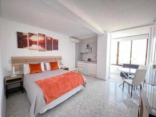 een slaapkamer met een bed, een bureau en een keuken bij Luceros 310 New in Alicante