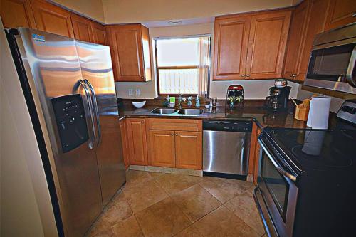a kitchen with wooden cabinets and a stainless steel refrigerator at Cozy House in SE Cape Coral. Pet-friendly! in Cape Coral