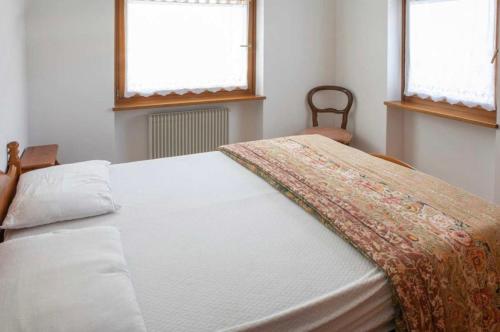 een bed in een slaapkamer met 2 ramen bij Residence Malibu Appartamento 2 in Falcade