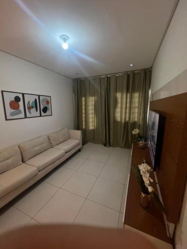 ein Wohnzimmer mit einem Sofa und einem TV in der Unterkunft Quarto em casa compartilhada in Petrolina