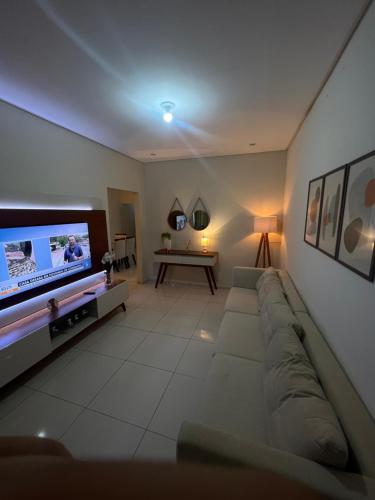 ein Wohnzimmer mit einem Sofa und einem Flachbild-TV in der Unterkunft Quarto em casa compartilhada in Petrolina