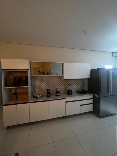 eine Küche mit weißen Schränken und einem Kühlschrank in der Unterkunft Quarto em casa compartilhada in Petrolina